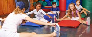 Children,doing,gymnastics,in,gym,of,preschool,with,nursery,teacher