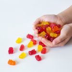 Kid's,hands,with,colored,gummi,bears,,chewing,vitamins,,healthy,candies